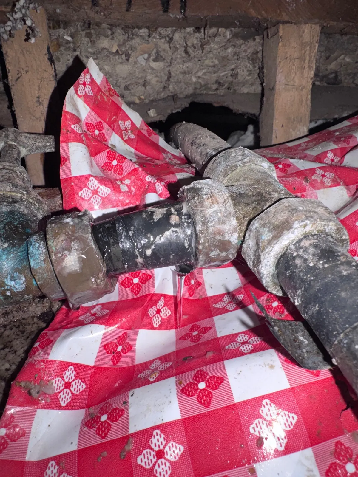 Old imperial-sized plastic supply pipe and stopcock joints exposed under a church hall floor